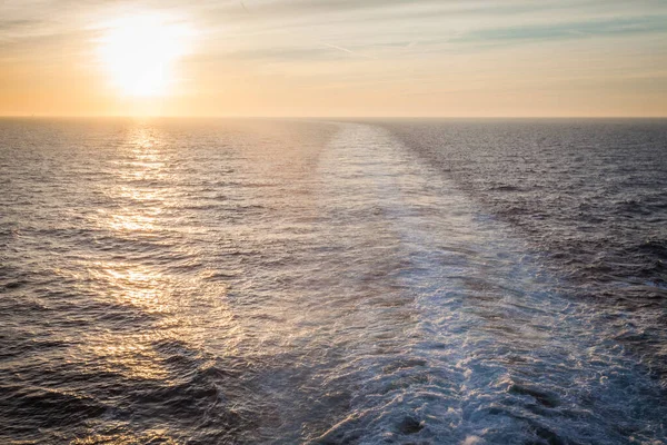 Weerspiegeling van de prachtige zonsondergang boven de zee en wakker achtergelaten door een cruiseschip — Stockfoto