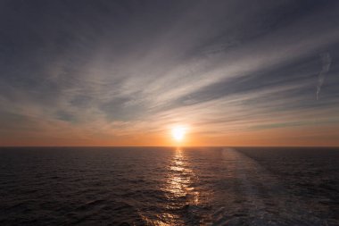 Deniz üzerinde rüya gibi gün batımının yansıması ve bir yolcu gemisi tarafından terk edilmiş olarak uyanmak