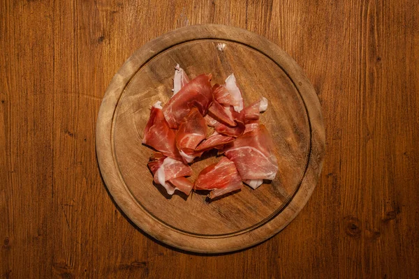 Top view of wooden plate with speck slices — Stock Photo, Image