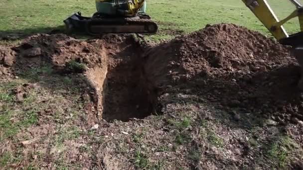 Pá mecânica preenchendo um buraco em um prado com cascalho — Vídeo de Stock