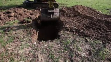 Mekanik kürek çayırda çukur kazıyor.