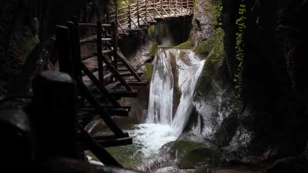 Effet cinématographique des chutes d'eau dans une grotte avec une passerelle en bois — Video