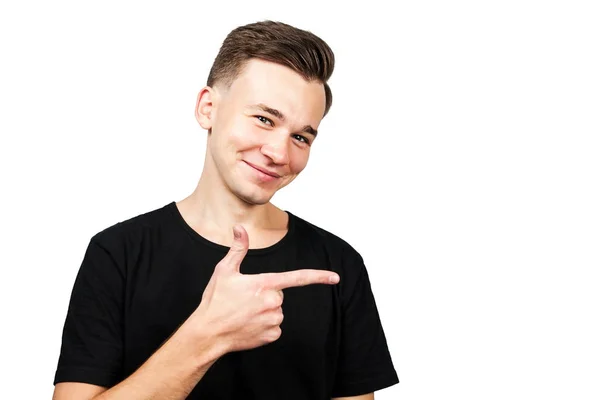 白人の若い男を着た黒 t シャツ ポイント脇人差し指と分離の白い背景の上の微笑. — ストック写真