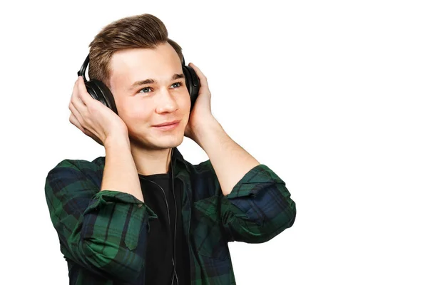 Porträtt profil av en kaukasiska vit ung kille lyssna musik i örat-telefoner. Stilig man klädd i en svart T-shirt och en grön rutig skjorta på vit isolerade bakgrund — Stockfoto