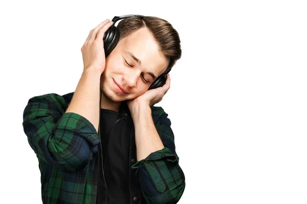 Портрет білого хлопця, який слухає музику в навушниках з закритими очима. Красивий чоловік одягнений у чорну футболку та зелену сорочку на білому ізольованому фоні — стокове фото