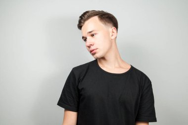 Beyaz genç adam beyaz arka plan gülümsüyor ve bir kenara seyir siyah t-shirt giymiş.