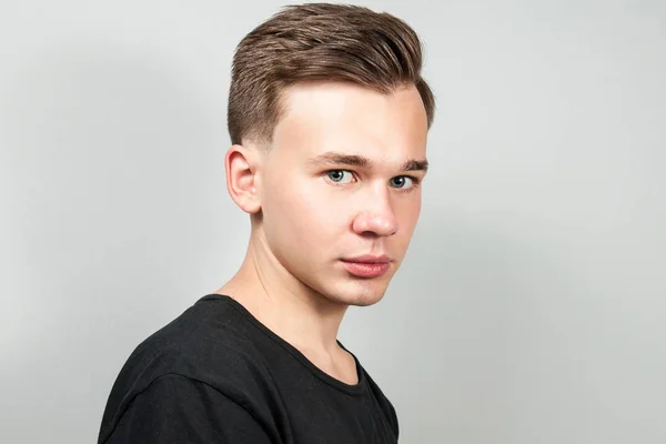 White young guy dressed in a black t-shirt on white background looking. — Stock Photo, Image