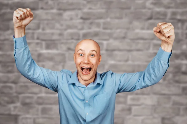 Retrato Hombre calvo blanco en camisa azul sobre fondo de pared de ladrillo blanco mostrando pulgares hacia arriba y sonriendo —  Fotos de Stock