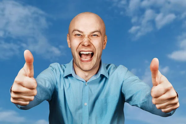 Retrato Hombre calvo blanco en camisa azul sobre fondo azul del cielo mostrando pulgares hacia arriba y sonriendo —  Fotos de Stock