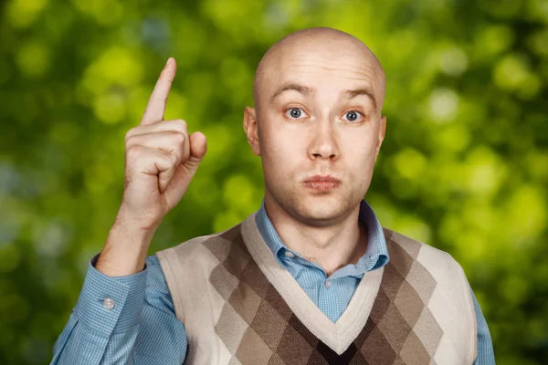 Porträtt Bald allvarliga mannen punkter och hotar med pekfingret på grön bokeh bakgrund — Stockfoto