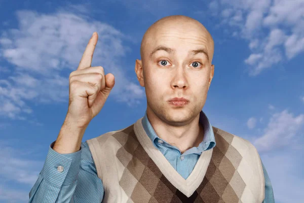 De kale ernstige mens van het portret richt en dreigt met wijsvinger op blauwe hemel achtergrond — Stockfoto