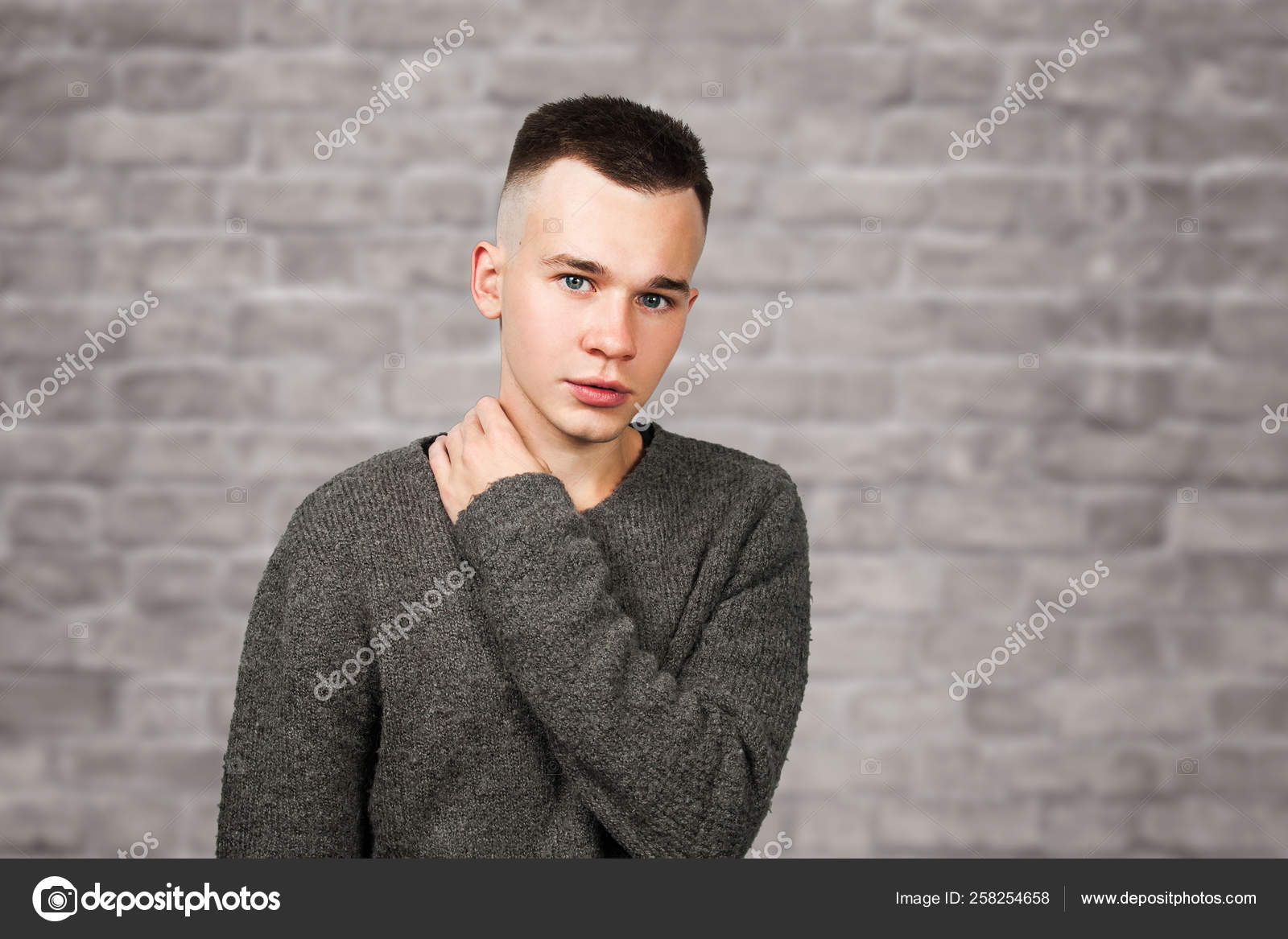 Portrait Of White Yong Guy In Gray Sweater And Short Haircut On
