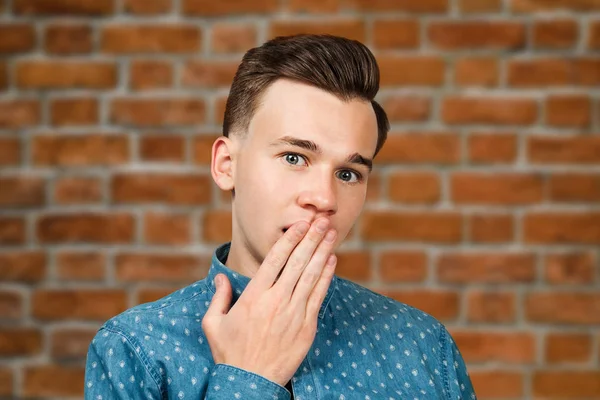 Portrait young guy dressed blue shirt. man open his eyes wide with hands, fingers and mouth. Man on brick wall background — Stock Photo, Image
