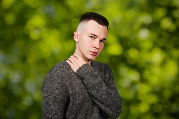 Portrait de type yong blanc en pull gris et coupe de cheveux courte, sur fond bokeh vert — Photo