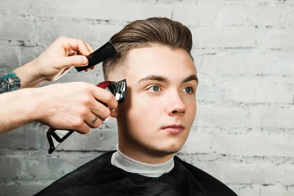 Friseur Frisur junger Kerl im Friseursalon auf Backsteinmauer Hintergrund, Friseur macht Frisur für einen jungen Mann. Pompadour-Frisur. — Stockfoto