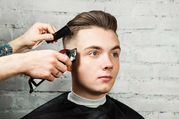 Berber saç tuğla duvar arka plan üzerinde berber dükkanında genç adam şekillendirme, kuaför genç bir adam için saç modeli yapar. Pompadour saç modeli.