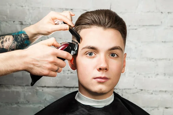 Cabelo de barbeiro styling de cara jovem na barbearia no fundo da parede de tijolo, cabeleireiro faz penteado para um jovem. Penteado Pompadour . — Fotografia de Stock