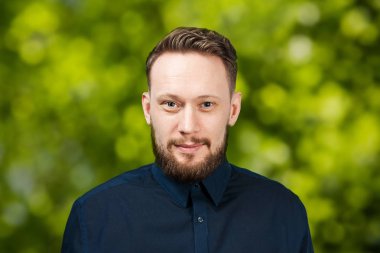 Yeşil bokeh arka plan üzerinde yakışıklı yetişkin adam Portresi. Sakallı beyaz adam gülümsüyor. Işadamı.