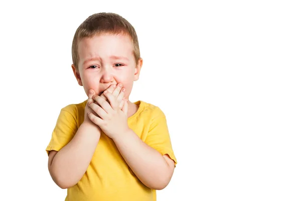 Chorando menino em uma camiseta amarela cobre seu rosto com mãos e gritos, estúdio isolado no fundo branco — Fotografia de Stock