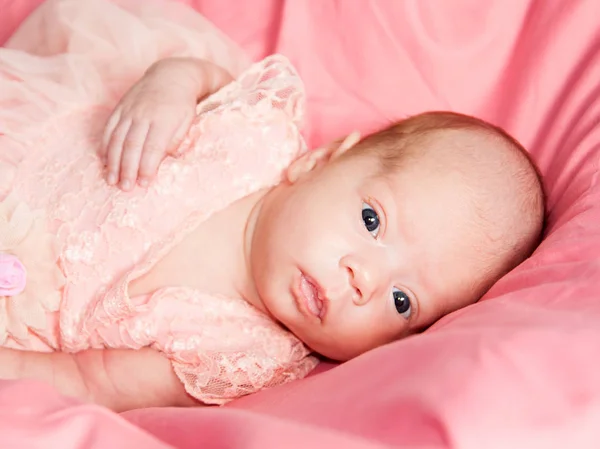 Menina recém-nascida em vestido rosa e coroa de crochê, encontra-se na cama rosa . — Fotografia de Stock