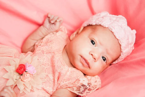 Menina recém-nascida em vestido rosa e coroa de crochê, encontra-se na cama rosa . — Fotografia de Stock