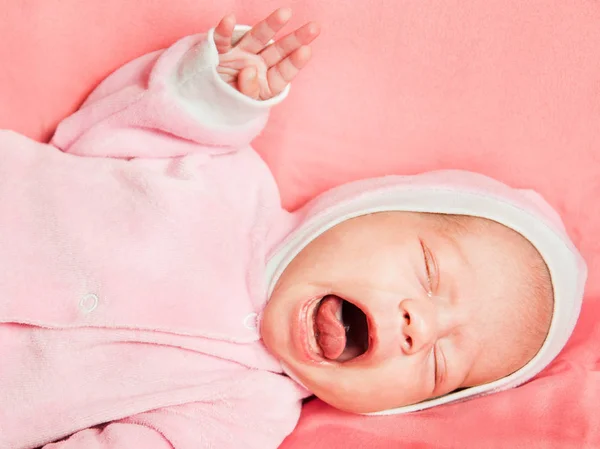 Retrato de cerca de una niña recién nacida vestida con un vestido rosa, con una corona y una flor en la cabeza — Foto de Stock