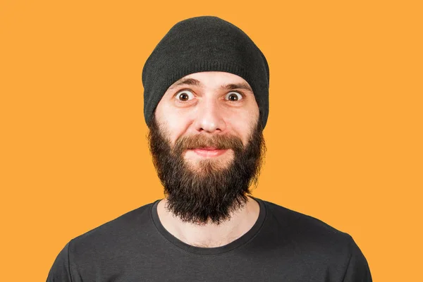 Young bearded guy in hat, with open eyes. Isolated on orange background — Stok fotoğraf