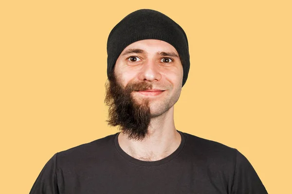 Mladík v klobouku s napůl oholeným vousatým úsměvem. Izolované na oranžovém pozadí. — Stock fotografie