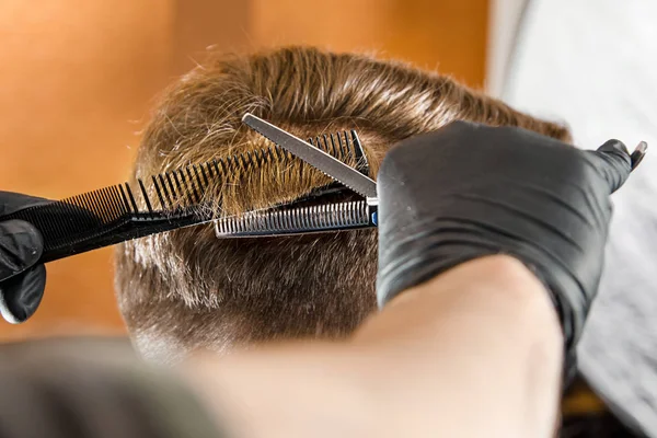 Friseurhände schneiden Haare und kämmen erwachsenen Mann auf einer Ziegelwand Hintergrund. Nahaufnahme Porträt eines Mannes — Stockfoto