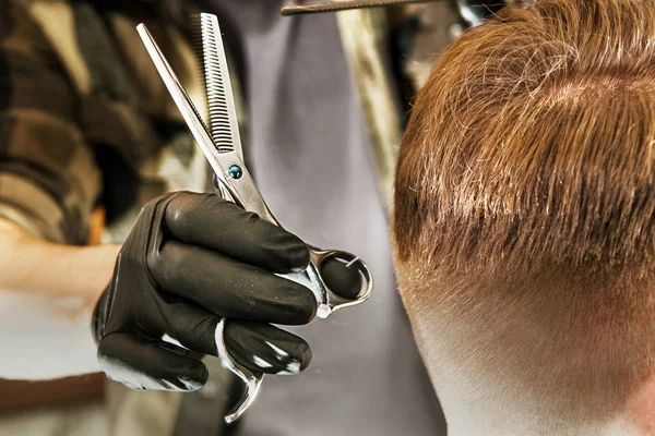 Barbeiro mãos cortar o cabelo e pentear pente homem adulto em um fundo de parede de tijolo. Close up retrato de um cara — Fotografia de Stock