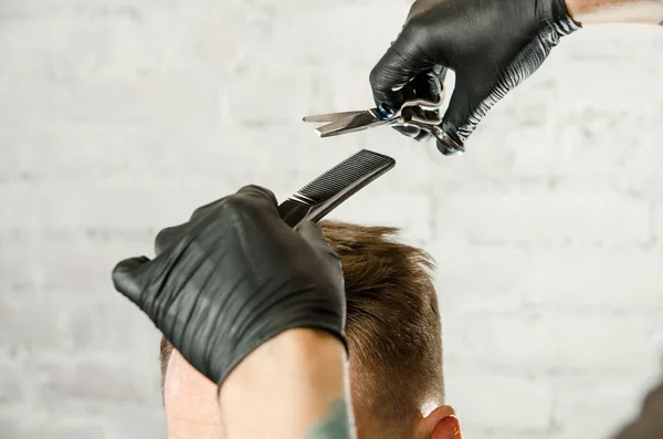 Fryzjer ręce cięte włosy i czesanie grzebień dorosłego człowieka na tle muru ceglanego. Zbliżenie portret faceta — Zdjęcie stockowe