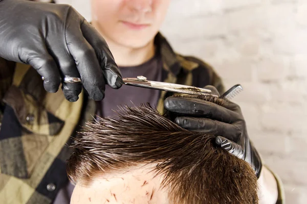 Fodrász vágott haj és fésű felnőtt ember egy téglafal háttérben. Közelről portré egy srác — Stock Fotó