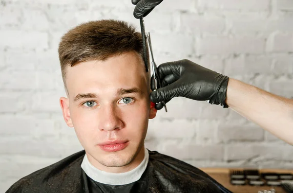 Friseur schneiden Haare und Kamm Mann auf einer Backsteinmauer Hintergrund. Nahaufnahme Porträt eines Mannes — Stockfoto