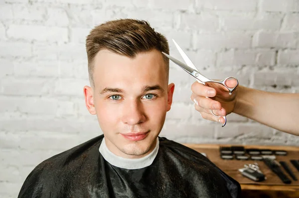 Friseur schneiden Haare und Kamm Mann auf einer Backsteinmauer Hintergrund. Nahaufnahme Porträt eines Mannes — Stockfoto