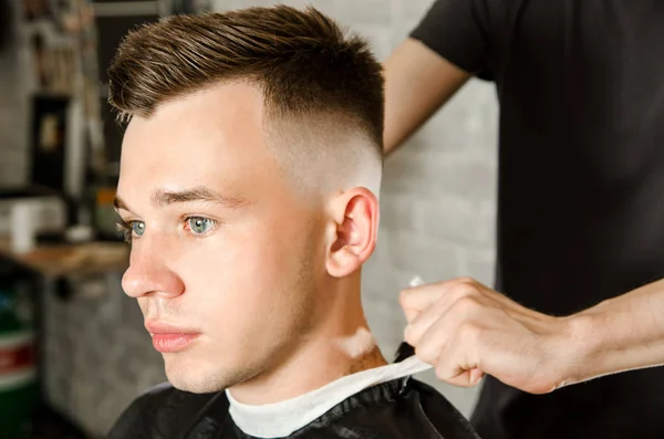 Barber cleans the neck of a young guy with a brush with talc after a haircut on a brick wall background — Stock Photo, Image