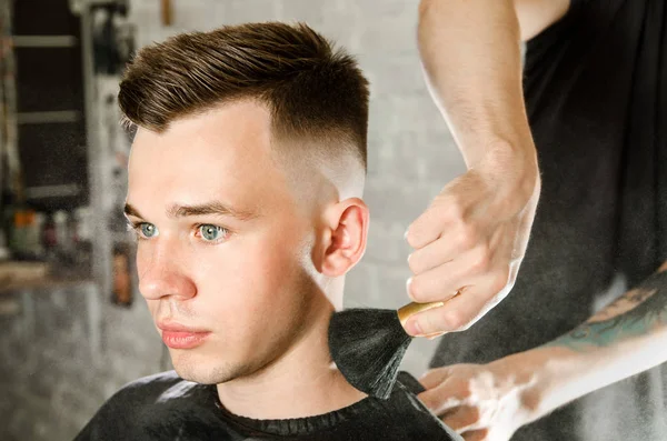 Friseur reinigt nach einem Haarschnitt auf Backsteinmauer den Hals eines jungen Mannes mit einem Pinsel mit Talkum — Stockfoto