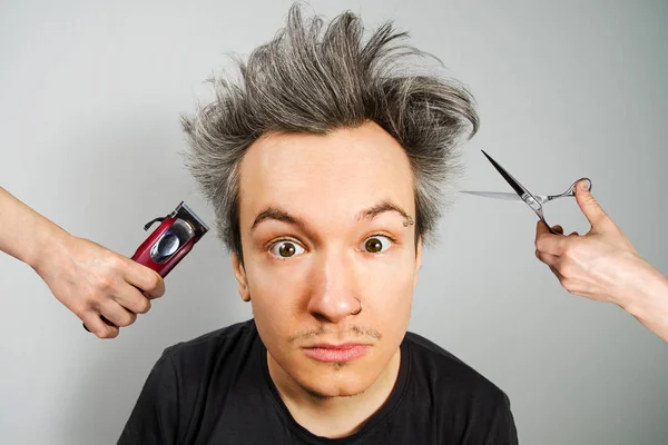 Hand met Clipper en hand met schaar cut begroeid ongeschoren kerel met op een grijze achtergrond — Stockfoto