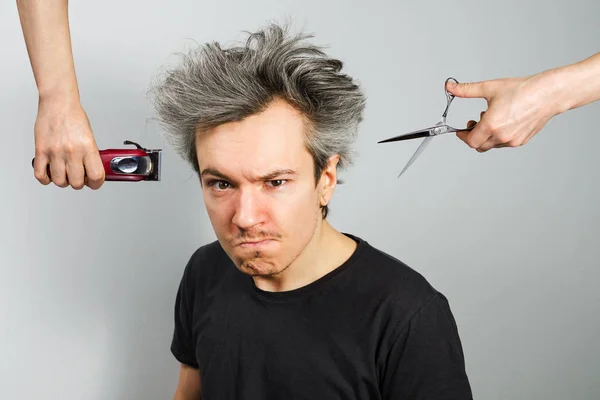 Hand met Clipper en hand met schaar cut begroeid ongeschoren kerel met op een grijze achtergrond — Stockfoto