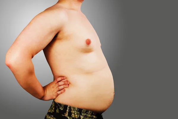 Body fiatal férfi a túlsúly, tartsa hasa kövér, a szürke háttér. — Stock Fotó