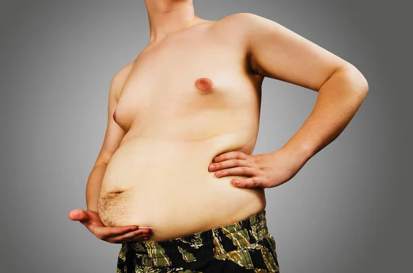 Тіло молодого чоловіка з надлишковою вагою, тримайте жир живота, на сірому фоні . — стокове фото