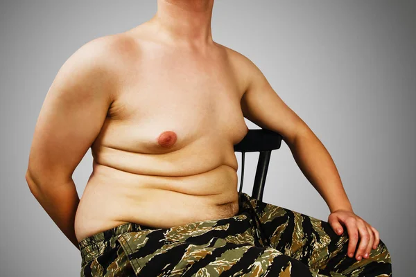 Kroppen av ung man med övervikt, hålla magen fett, på en grå bakgrund. — Stockfoto