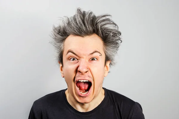 Sad anger young guy look in camera and cry with wide eyes and scream, on gray background. — Stockfoto