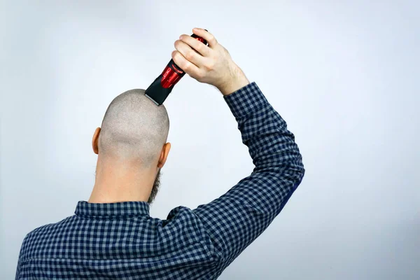 Portrait of back bald man head holding a trimmer in his hand. The concept of hair loss and hair transplantation