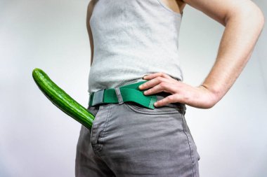 A man imitates a penis with a cucumber. concept of men's health, potency and large size.
