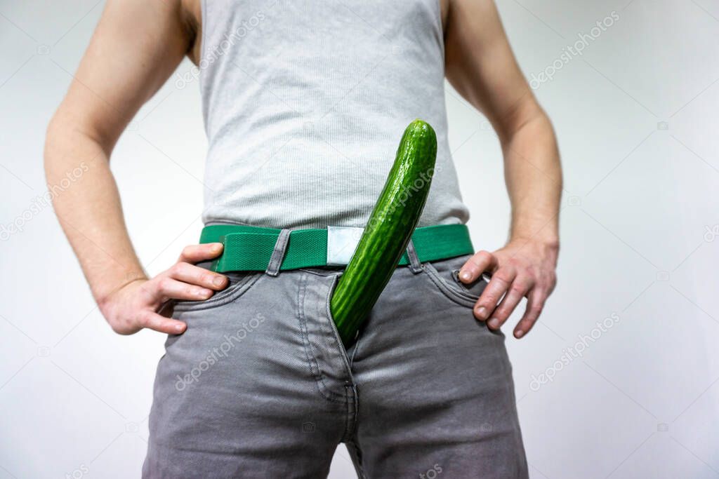 A man imitates a penis with a cucumber. concept of men's health, potency and large size.