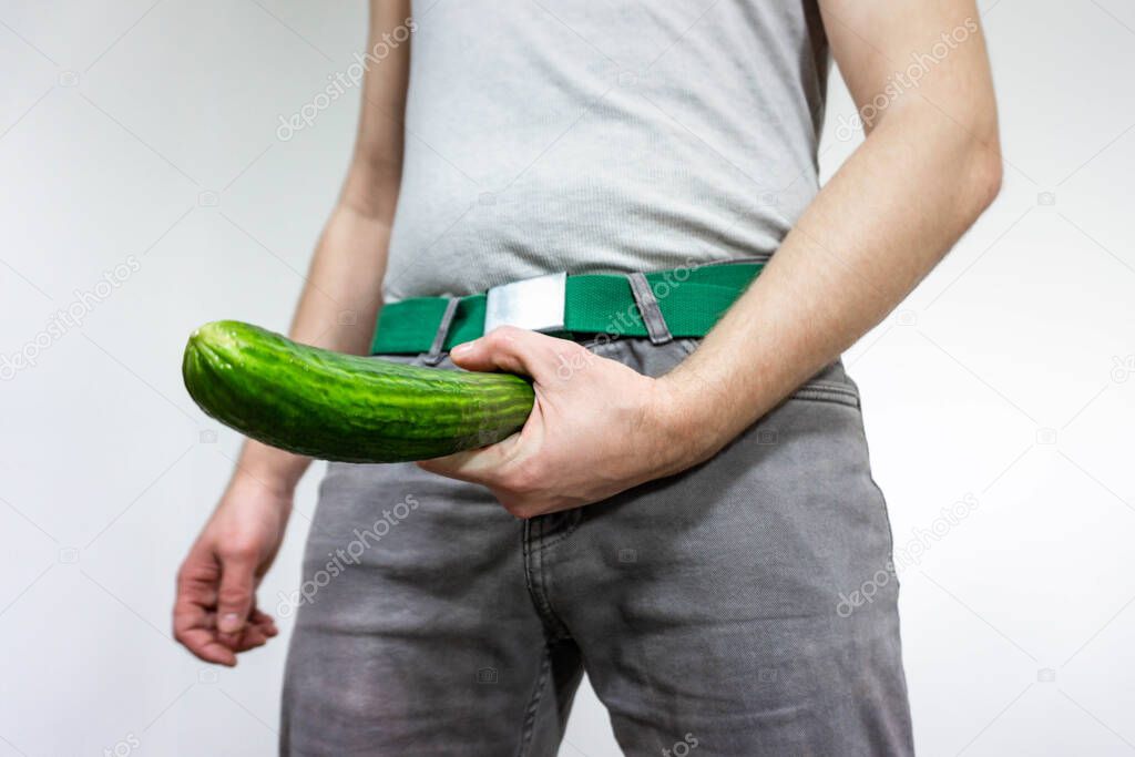 A man imitates a penis with a cucumber. concept of men's health, potency and large size.