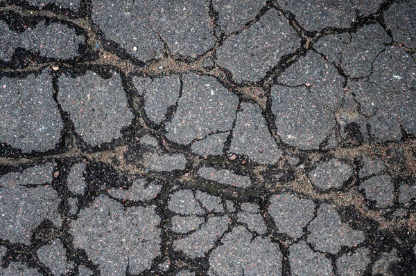 De weg is heel slecht en oud. Textuur van versleten en gebarsten asfalt met scheuren. — Stockfoto