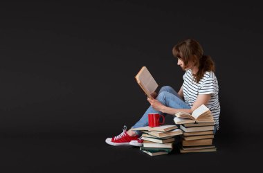Bir kız siyah arka planda bir kitap okuyor. Bağımsız öğrenim kavramı.