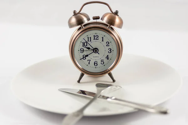 copper look clock with knife and fork in white background