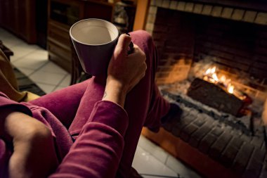 kahve içiyor iken kadın bir şömine ısınıyor